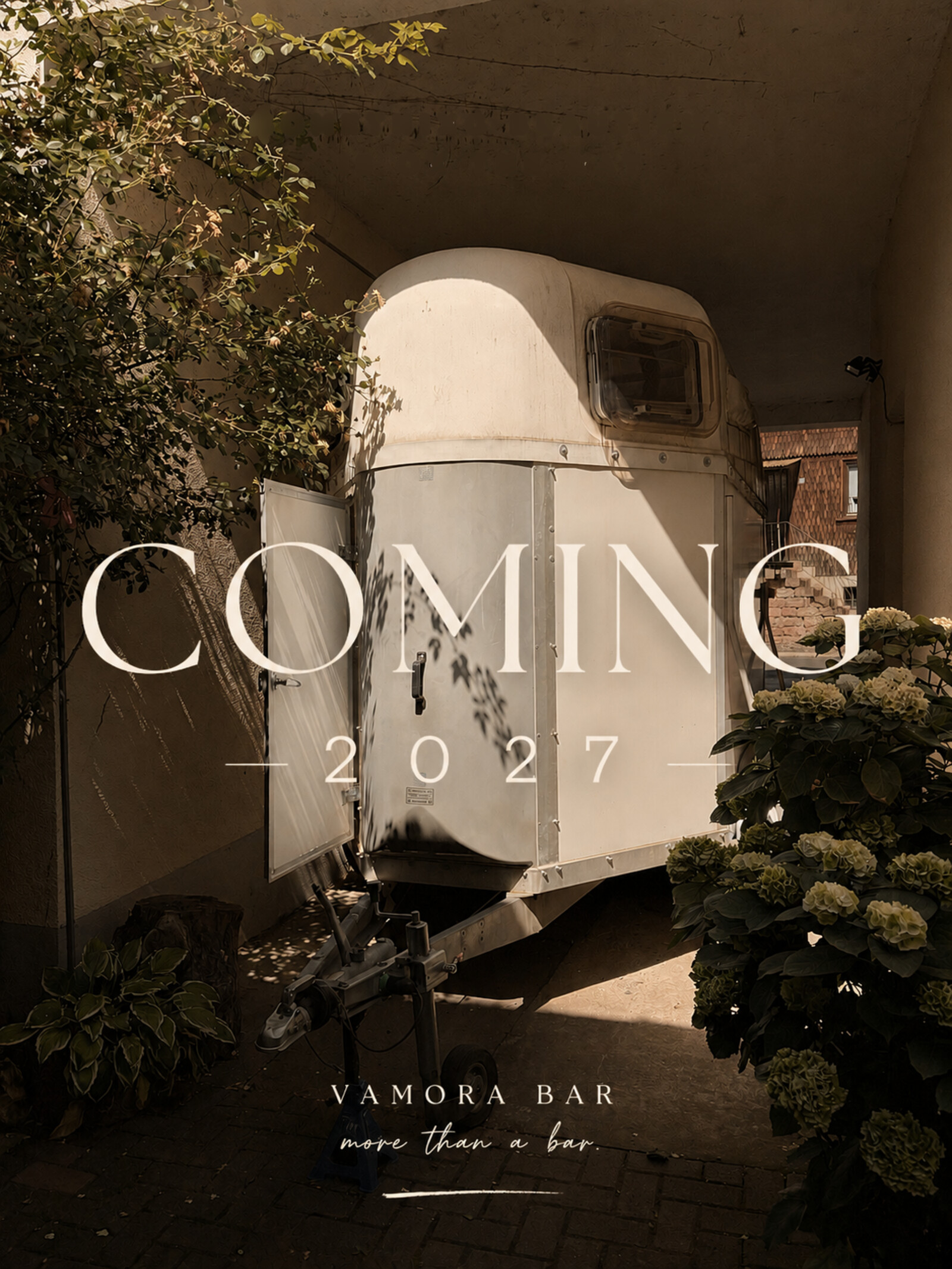 Coming 2027: der originale Pferdeanhänger der Vamora Bar vor dem Umbau, im Hof zwischen Hortensien